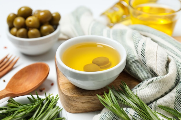Olive branches oil and olives in bowls towels on white background close up