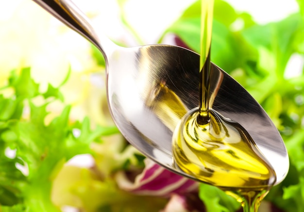 Foto l'olio d'oliva viene versato in un cucchiaio sull'insalata