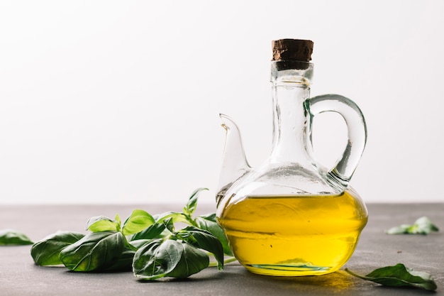 Olive oil bottle reflecting light with spinach around