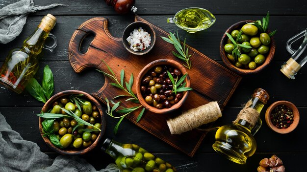 Olive oil and olives on a black wooden background