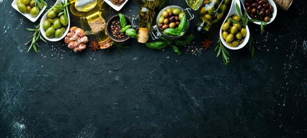 Olive oil olives and spices on a black stone background Top view Free space for your text