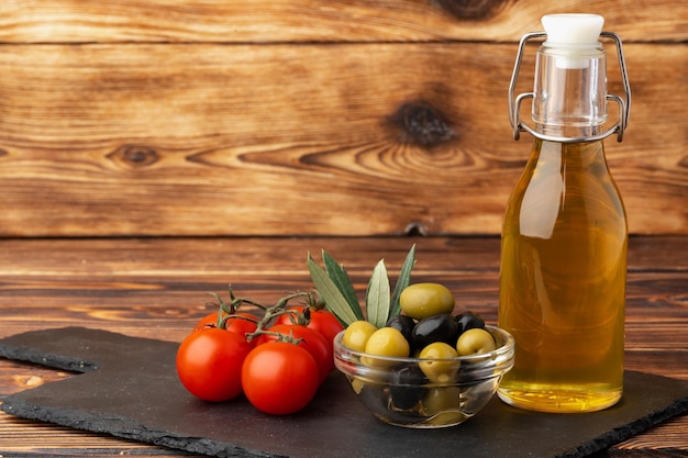 Olive oil olives and tomatoes on wooden background