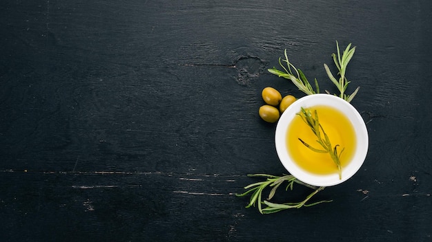 Olive oil in a plate and rosemary On a black wooden background Free space for text