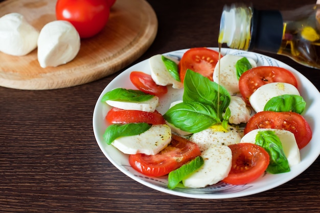 Photo olive oil pouring on caprese salad