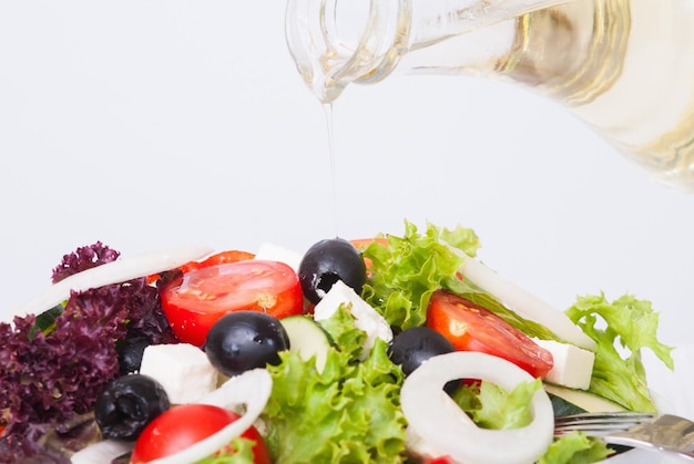 olive oil pouring into bowl of salad