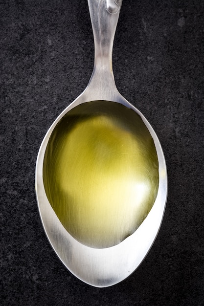 Olive oil on a spoon on black slate.