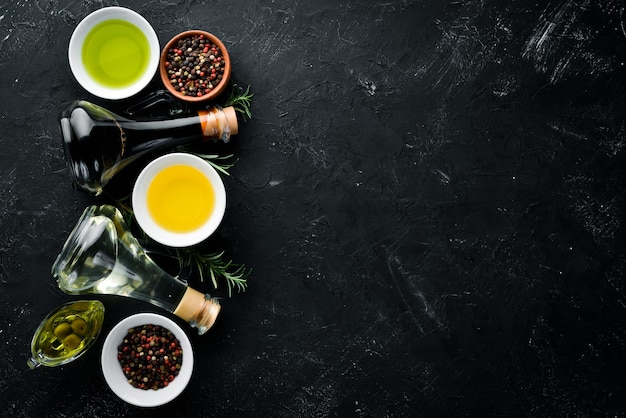 Olive oil sunflower oil and rosemary On a black stone background Top view Free copy space