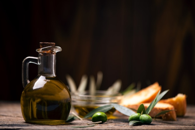 Оливковое масло с хлебом на деревянном столе. Деревенская винтажная композиция