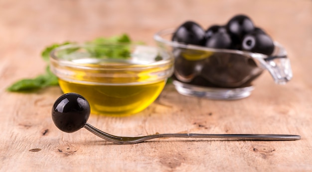 Olive oil with fresh herbs and olive on fork  on wooden wall