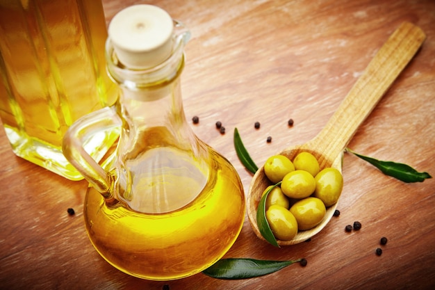 Olio d'oliva con olive fresche su legno rustico