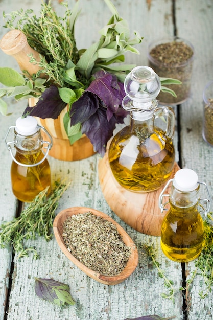 Photo olive oil with herbs and spices on wooden background