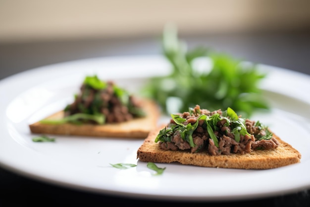 Olive tapenade on a pita chip with a parsley leaf