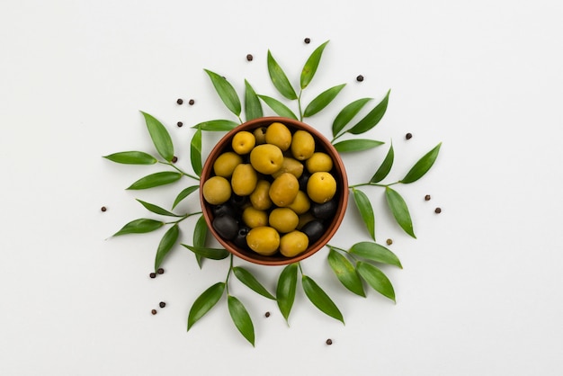 Photo olives in bowl with leaves next on table