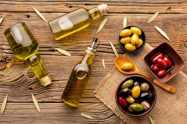 Olive in ciotole bottiglie di olio e foglie su materiale tessile