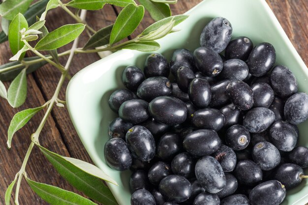 Olives in ceramic bowl on wooden background