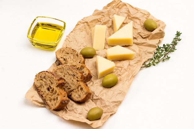 Бумага, оливки, сыр пармезан и веточки тимьяна. Вид сверху.