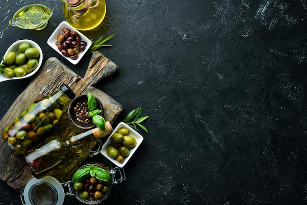 Olives A set of colored olives on a black stone background Top view Free space for your text