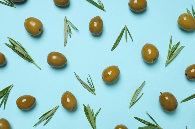 Olives and tree leaves on blue background top view