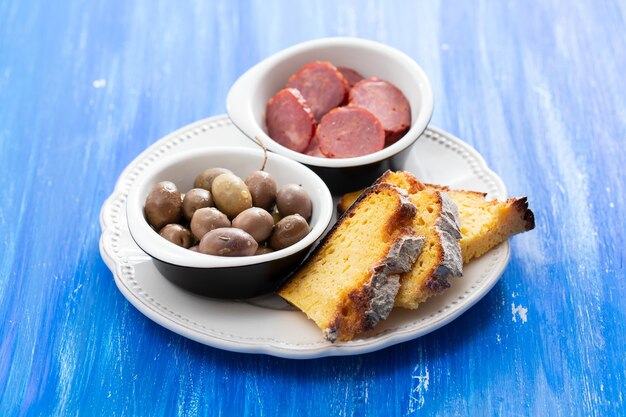 Olives with smoked sausages and corn bread