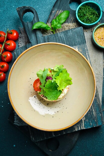 Olivier's classic salad with vegetables and mayonnaise On a black stone background In a plate closeup