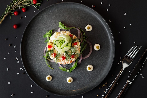 Olivier salad for Christmas on a black table, European holiday food