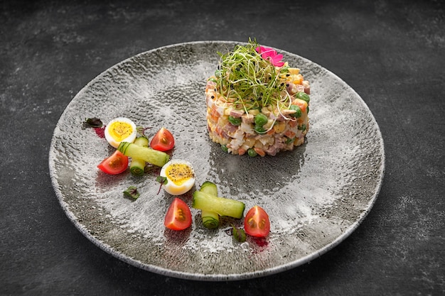 Olivier salad on a gray beautiful plate on a dark background restaurant serving