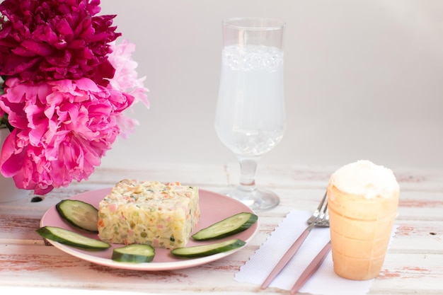 Olivier salad on a plate Bouquet of fragrant peonies serving dishes in the restaurant