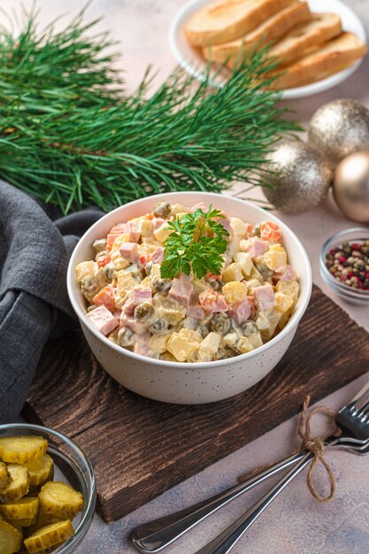 Olivier salad of vegetables, sausage, eggs and mayonnaise on a light background. Traditional festive salad in Russia.
