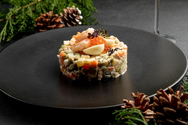 Insalata olivier con caviale rosso, su sfondo scuro di natale. piatto tradizionale russo per capodanno e natale.