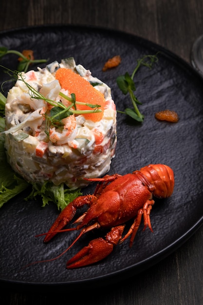 Olivier salad with red caviar served with boiled crayfish and wine