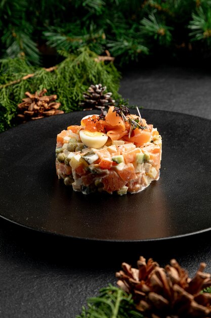 Olivier salad with salmon, on a dark Christmas background. traditional Russian poisoning for New Year and Christmas.