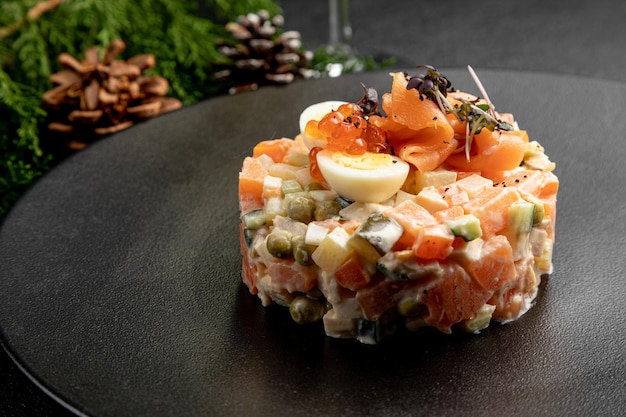 Olivier salad with salmon, on a dark Christmas background. traditional Russian poisoning for New Year and Christmas.