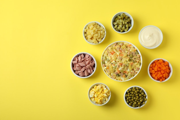 Olivier salade en ingrediënten op gele achtergrond