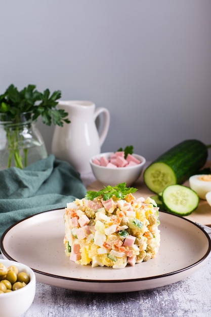 Olivier salade op een bord ingrediënten voor de bereiding op tafel Kerstsnacks Verticaal