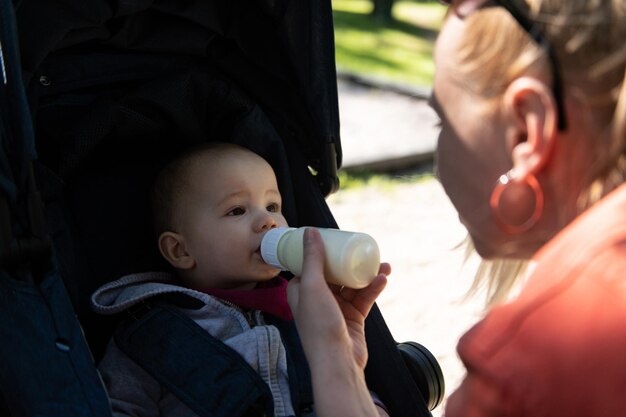 オムは幼児の男の子に飲み物を与えます