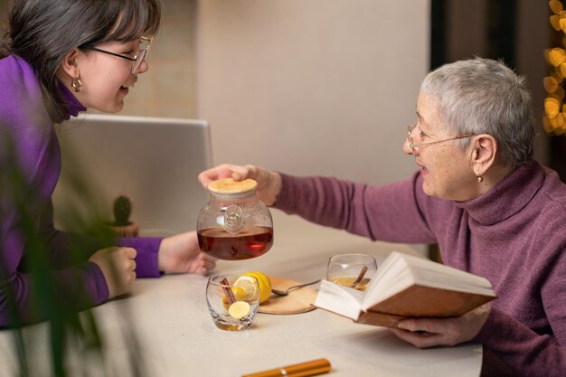 oma en kleindochter drinken thee zitten aan tafel en lezen een boek Selectieve focus