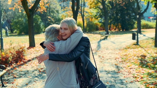 Oma en kleindochter knuffelen elkaar in park