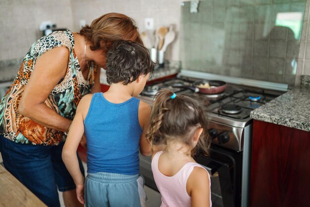 Oma leert de kinderen koken door naar de maaltijd in de oven te kijken.