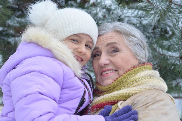 Oma met kleindochter glimlachend, buiten poseren in de winter