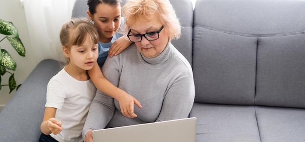 Oma met kleindochters gebruiken een computer.