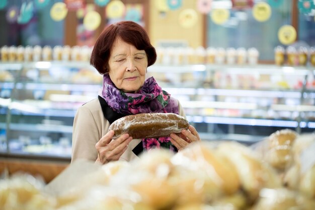 Oma vrouw tijdens het winkelen brood bij supermarkt winkel winkel