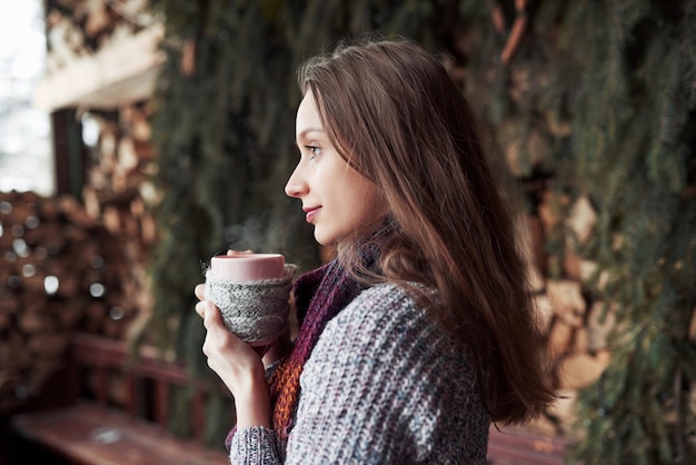 Oman wearing warm knit clothes drinking cup of hot tea or coffee outdoors