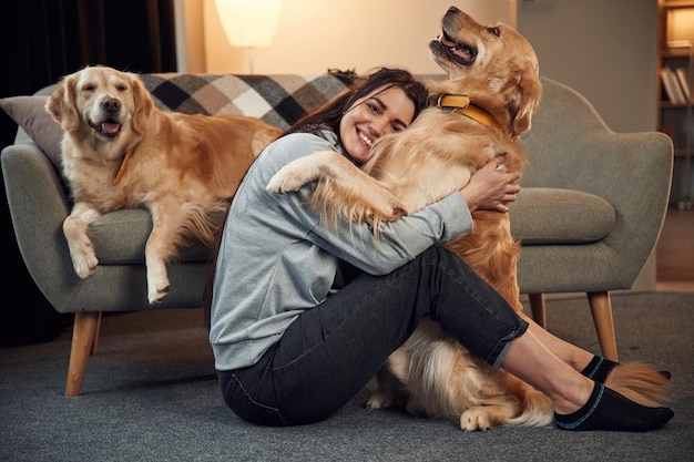 Omarmen en plezier maken vrouw is thuis met twee golden retriever-honden