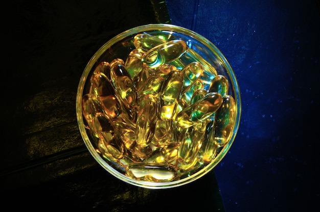 Omega 3 capsule. In a glass bowl on a colored background.