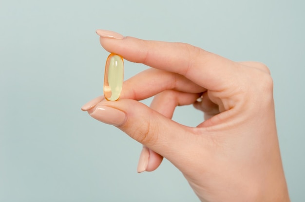 Omega 3 capsule in menselijke hand close-up op blauwe achtergrondkleur gezond eten en dieet