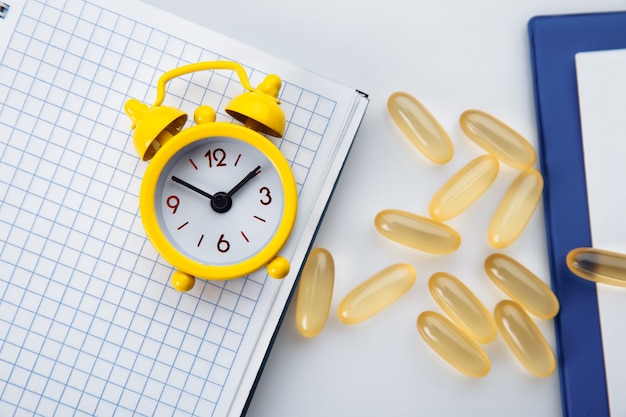 Omega 3 capsules and alarm clock on doctor desk