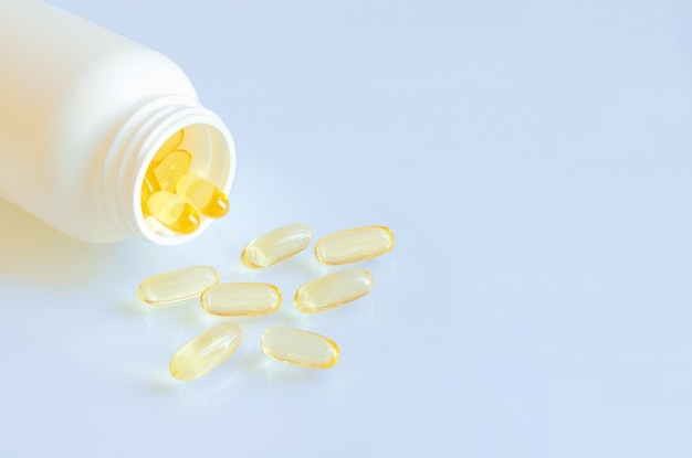 Omega 3-capsules die uit een fles op een lichte achtergrond worden gegoten