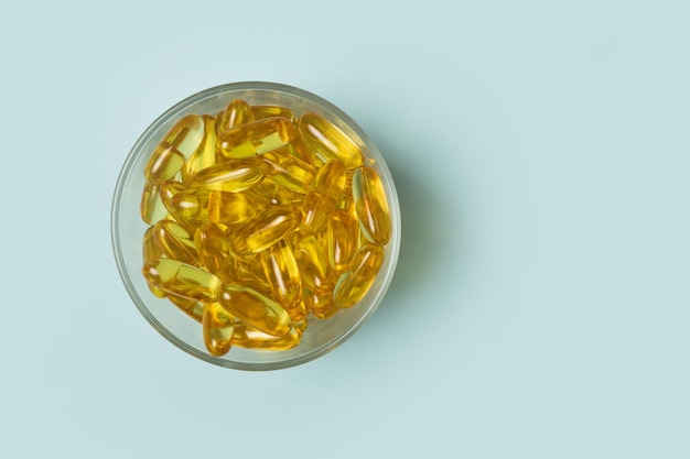 Capsule di omega 3 che giacciono in una ciotola su uno sfondo blu