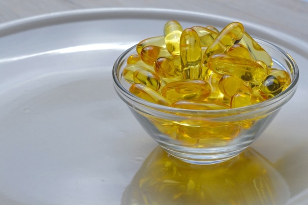 Omega-3 en vitamine D visolie capsules in een glazen plaat.