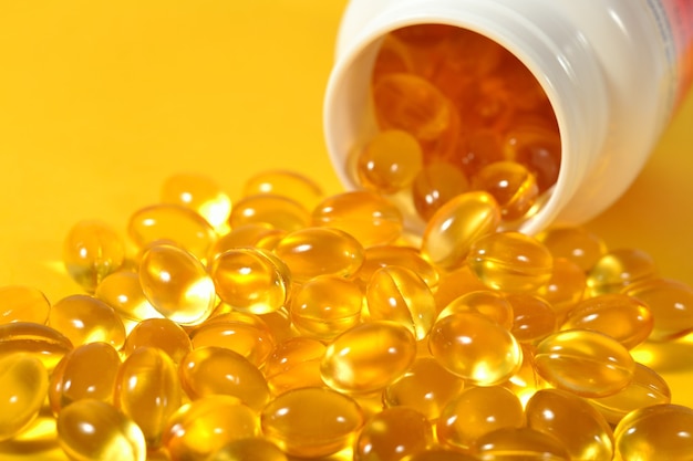 Omega-3 fish fat oil capsules spill out from bottle